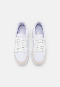 Paire de baskets blanches avec tige en mesh, bouts en cuir suédé et lacets, vues de dessus sur fond uni.