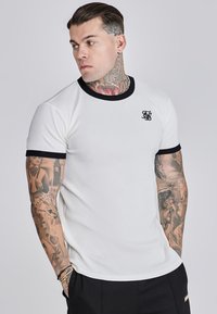 Wit T-shirt met korte mouwen, zwarte ribkraag en -manchetten, met een klein zwart logo op de borst en een getailleerde pasvorm.