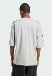 T-shirt in cotone grigio con maniche corte, scollo tondo e dettagli neri sulle spalle. Design semplice senza motivi o loghi.