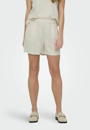 Lichtbeige shorts met een elastische tailleband, gemaakt van een gestructureerde, geweven stof. Gecombineerd met een bijpassende losse top en lichte schoenen.