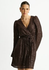 Brown sequin dress with a V-neck, long puff sleeves, and a waist tie. Designed with a textured surface and a short length.