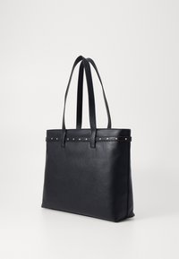 Bolso tote de cuero negro con un acabado texturizado, que cuenta con dos asas largas y una fila de pequeños clavos decorativos en la parte superior.