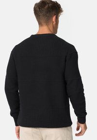 Zwarte textuurtrui met een ronde hals, geribbelde manchetten en horizontale panelen op de rug. Gemaakt van comfortabele breip stof.