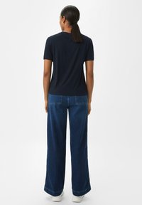 Marineblaue Kurzarm-T-Shirts mit rundem Ausschnitt, kombiniert mit hochtaillierten, weit geschnittenen Jeans. Die Textur wirkt weich, das Design ist lässig.