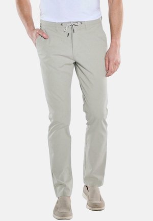 Helle graue Hose, schlanke Passform, aus weichem Stoff. Elastischer Bund mit Kordelzug. Mit minimalistischen Taschen gestaltet. Kombiniert mit beigen Schuhen.