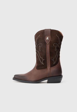 Bruna lädercowboystövlar med ett mockaskaf, detaljerad sömnad, spetstopp och en låg svart klack. Dekorativa vita mönster synliga.