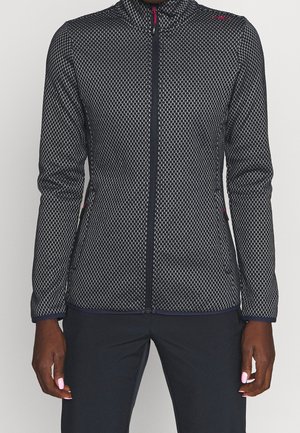 Fleece bunda s vysokým límcem, námořnická modrá s bílým šestiúhelníkovým vzorem, plný zip a přiléhavý střih. Má růžové detaily na zipu.
