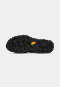 Suola di scarpa outdoor nera con un pattern di gomma testurizzata. Caratterizzata da scanalature profonde per una buona presa e un logo Vibram giallo sul lato.