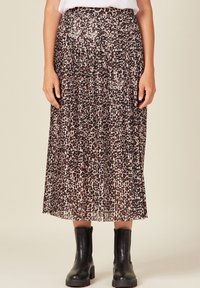 Gonna midi plissettata in fantasia leopardata con tonalità di marrone e crema, realizzata in tessuto leggero, abbinata a stivali neri alla caviglia.