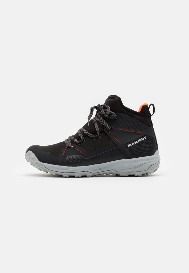 Scarpa da trekking nera con suola grigia, tessuto leggero, punta rinforzata e dettagli arancioni. Caratterizzata da una rete traspirante e una suola antiscivolo resistente.