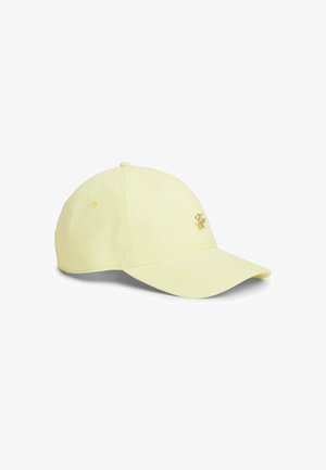 Casquette de baseball jaune pâle avec des rayures verticales discrètes et un petit emblème doré sur le panneau avant gauche, sur fond blanc.
