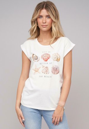 White cotton t-shirt featuring colorful shell and starfish graphic with text "Life is better at the beach," rounded neckline, and cap sleeves.