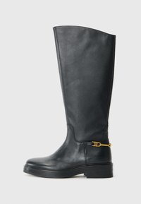 Botte en cuir noire jusqu'au genou avec une semelle épaisse et une petite boucle décorative dorée près de la cheville sur un fond blanc.