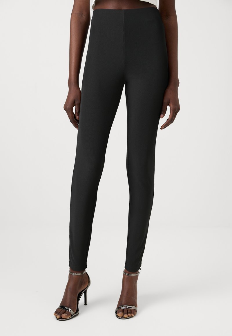 Leggings noirs taille haute avec une texture côtelée et une coupe slim. Assortis à des sandales à talons hauts avec des lanières. Design simple et minimaliste.