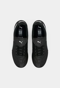 Pair of black Puma Liga soccer cleats with white Puma logo on tongue and sides, viewed from above on white background.