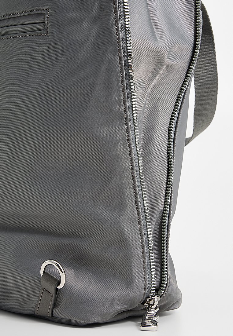 Grauer Nylonbeutel mit glatter Textur, seitlichem Reißverschluss mit metallischem Zipper und einem runden Hardware-Detail am Boden.
