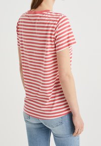 Červeno-bílý pruhovaný tričko s krátkým rukávem, kulatým výstřihem a volným střihem, vyrobené z měkké bavlny.