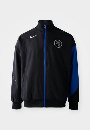 Chaqueta deportiva negra con acentos azules, que presenta un alto cuello, cierre con cremallera, bolsillos laterales y un logotipo circular en el pecho. Marca Nike.