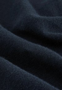 Mörk marinblå stickad tyg med en mjuk, något texturerad yta, som har släta vågor och fina ribbdetaljer.