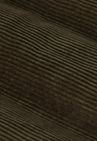 Tissu marron texturé avec des côtes visibles, présentant une texture douce et chaude. Le matériau semble lourd et durable, avec une couleur riche et terreuse.