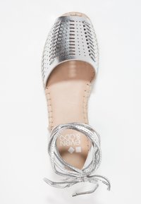 Höyryävä metallinhohtoinen avonainen espadrillesandaali, jossa on rei'itetty päällinen, ommeltu pohja ja ympärille solmittava nilkan nauha neutraalilla taustalla.