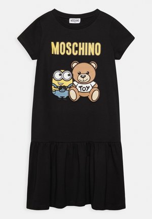 Sort kjole med korte ærmer og flæset skørt, med gul "MOSCHINO" tekst, en Minion-figur og en tøjbamse, der holder et "TOY" skilt på brystet.