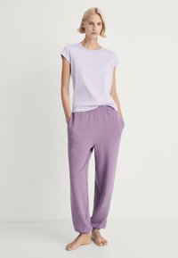 Lyse lilla bomulds t-shirt med korte ærmer parret med løstsiddende, lavendel joggerbukser med elastisk talje.