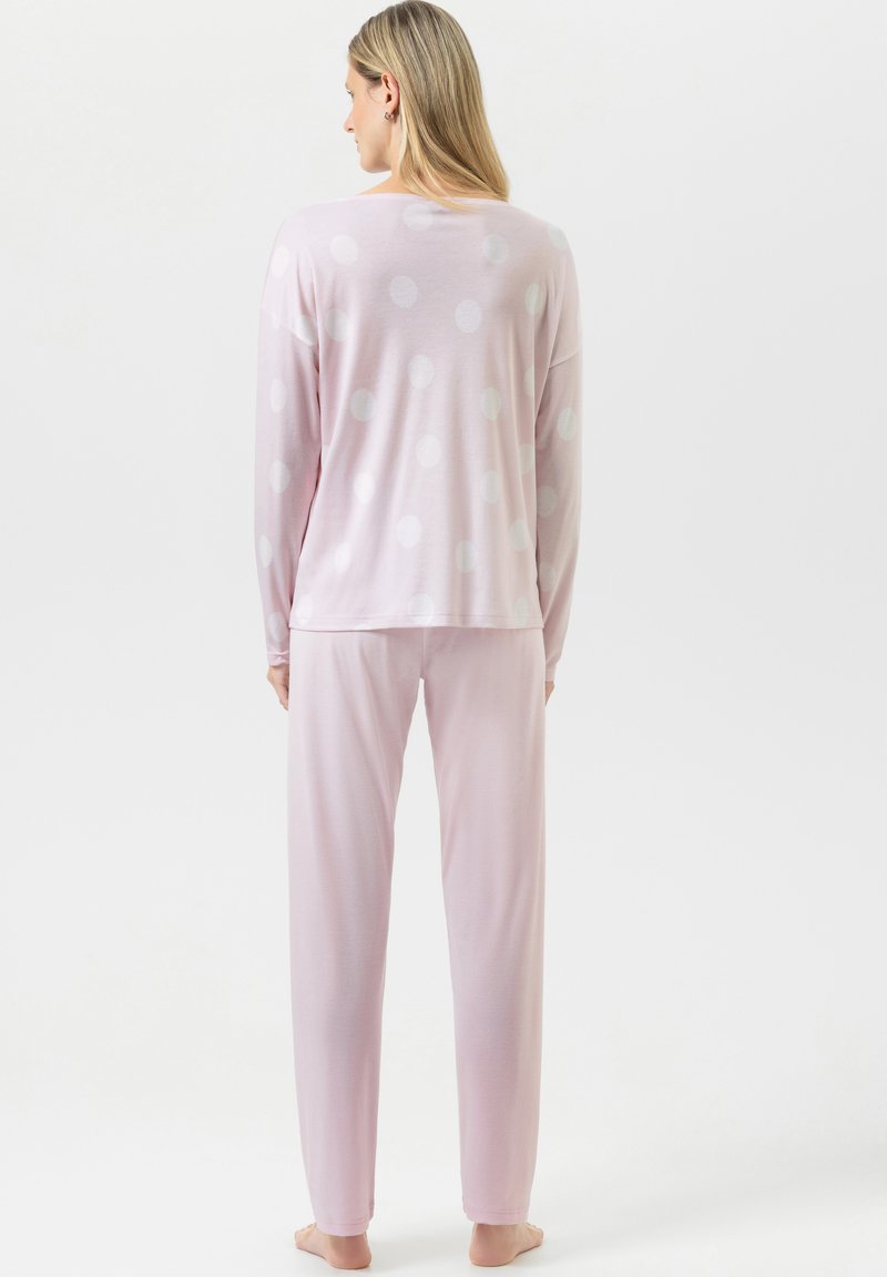 Ensemble de pyjama rose clair comprenant un haut à manches longues avec des pois blancs et un pantalon assorti. Tissu doux avec une coupe décontractée.