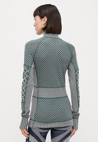 Langermet treningsgenser med en blanding av grønnfarger og stripemønstre, med høy hals og teksturert strikkemateriale.