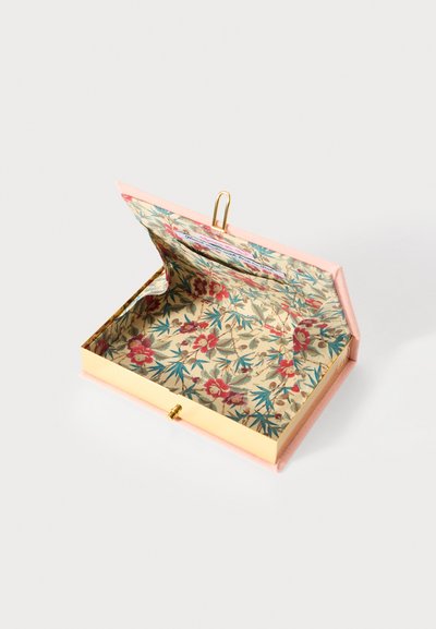 Boîte en métal doré avec un intérieur à motif floral et un extérieur en tissu rose doux. Ouverte avec un fermoir et une boucle d�écorative.