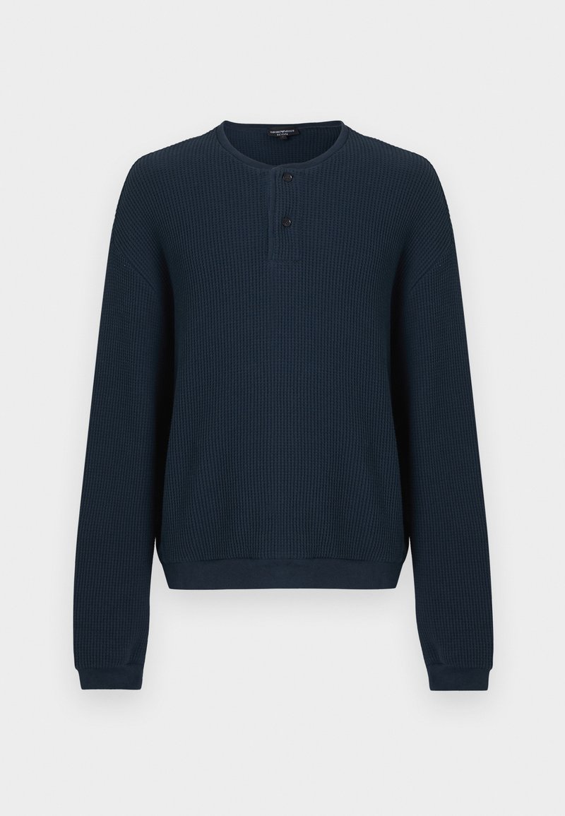 Pull bleu marine à manches longues en tissu côtelé texturé. Il présente un col rond et une patte de boutonnage à trois boutons. Les poignets et l'ourlet sont unis.