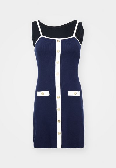 Vestido de punto azul marino con detalles blancos, que presenta un escote redondeado, botones dorados en el frontal y dos solapas de bolsillo blancas.