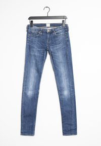 Jeans de mezclilla azul ajustados con un ligero desgaste, cinco bolsillos, cierre de botón y presillas para cinturón. Textura suave y diseño de pierna ceñida.