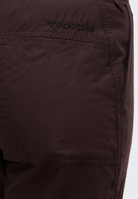 Σκούρο καφέ παντελόνι από υφασμάτινη υφή με κεντημένο λογότυπο «HOUDINI» πάνω από μία οριζόντια ραφή στο πάνω μέρος του ποδιού.