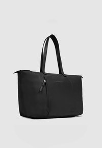 Zwarte tas met een gladde, matte afwerking. Voorzien van twee lange handvatten, een ritssluiting en een voorvak met rits. Minimalistisch ontwerp met logo.