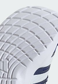 White rubber shoe sole with deep tread patterns; textured surface features curved and angular designs; blue accents visible on the side.