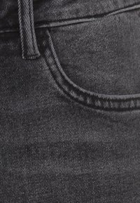 Μαύρα τζιν παντε�λόνια από τζιν με λεία υφή, εμφανή ραφές, εμπρόσθια τσέπη και εφαρμοστή μέση.