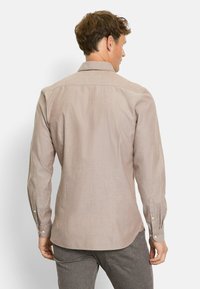 Hellbeige Langarmhemd mit Standardkragen, Knopfmanschetten und einer dezenten Textur. Es verfügt über einen abgerundeten Saum und einen Rückensteg.