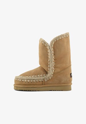 Stivale alla caviglia in suede beige con punta rotonda, cuciture decorative beige e accenti testurizzati lungo il bordo. Suola in gomma piatta.