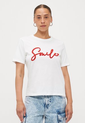 Tricou alb din bumbac cu text roșu pufoș „Smile”. Mâneci scurte și croială lejeră. Asortat cu pantaloni din denim de un albastru deschis.