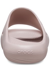 Roze rubberen sandaal met een open hiel, tekstuur op de voetbed en verhoogd "CROCS"-logo op de zijkant. Gladde materialen met een rond ontwerp.