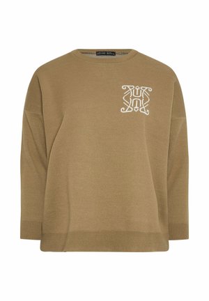 Ruskea neulepaita, jossa on pyöreä pääntie, pudotetut harteet ja valkoisella brodeerattu logo. Kädensuissa ja helmassa on ribbit tekstuurin lisäämiseksi.