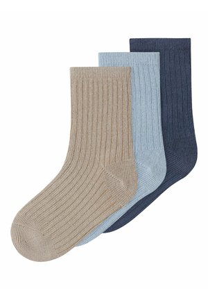 Three ribbed crew socks in beige, light blue, and dark blue, arranged overlapping on a white background.