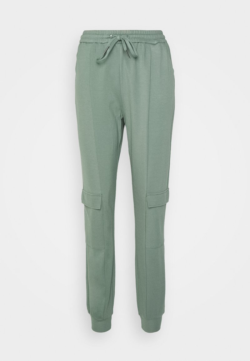 Calças de treino verdes feitas de um tecido suave, com uma cintura elástica ajustável, dois bolsos laterais e punhos ajustados. Projetadas com um detalhe de estilo cargo.