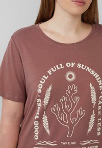 Bordeauxfarbenes T-Shirt mit Rundhalsausschnitt, das weißen Text und eine zentrale korallenfarbene Grafik mit dekorativen Elementen zeigt. Aus weichem Baumwollmaterial.