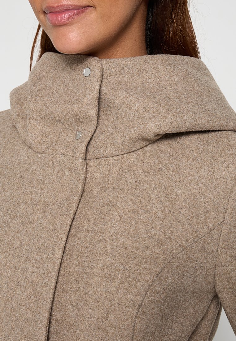 Abrigo de mezcla de lana beige con cuello alto, cierre de botones a presión y textura suave con sutiles detalles de costura.