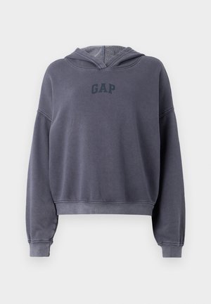 Haut à capuche gris coupé, fabriqué en tissu doux, arborant un logo "GAP" gris foncé sur la poitrine, des manches longues et une capuche.