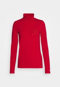 Red long-sleeve turtleneck top made of smooth fabric. Features a small, embroidered logo on the chest and fitted silhouette.