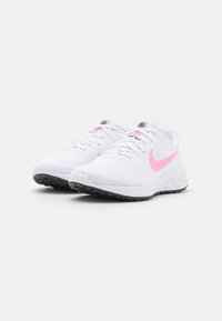 Bílé sportovní boty s růžovými akcenty, síťovaným svrškem, plochými tkaničkami, polstrovanou podrážkou a černou gumovou podrážkou, s logem na jazyku.