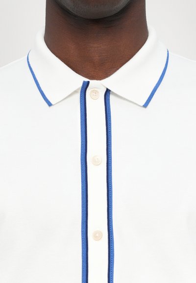 Tricou polo alb cu un accent albastru la guler și la plăcuța de butoane, cu trei butoane și un material texturat.